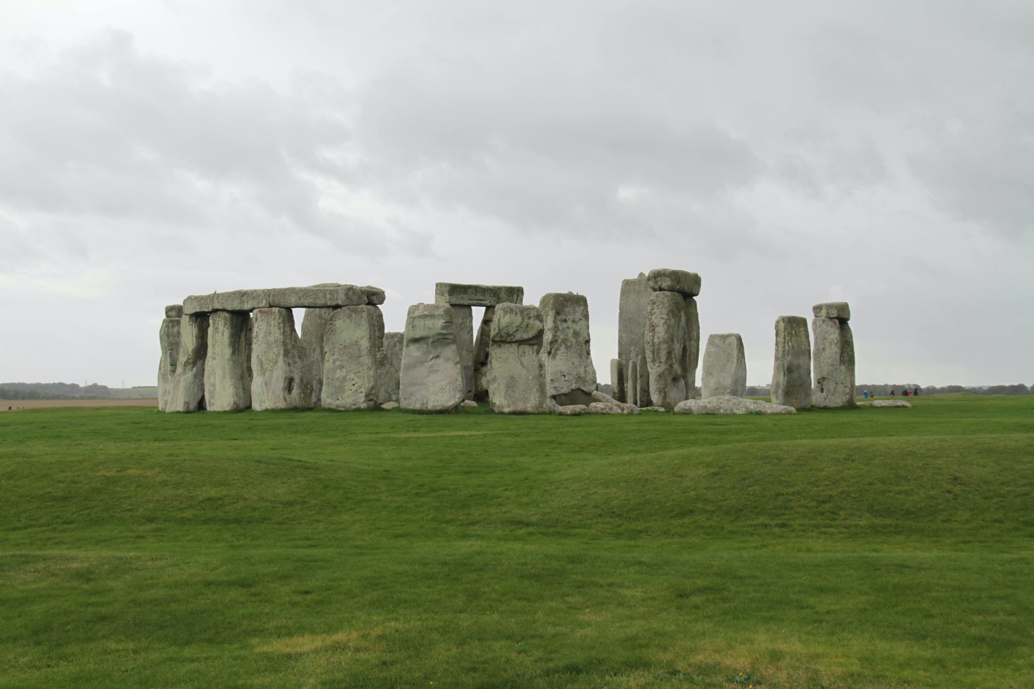 Capture of iconic Stonehenge stone circle under a dramatic cloudy sky, set in the green English countryside.